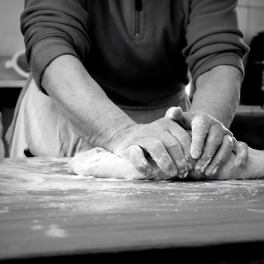 Hands dusting flour over dough